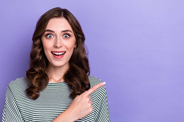 Photo of young excited surprise big season sale offer proposition finger directing mockup deal shopaholic crazy isolated on violet color background. - 写真・画像