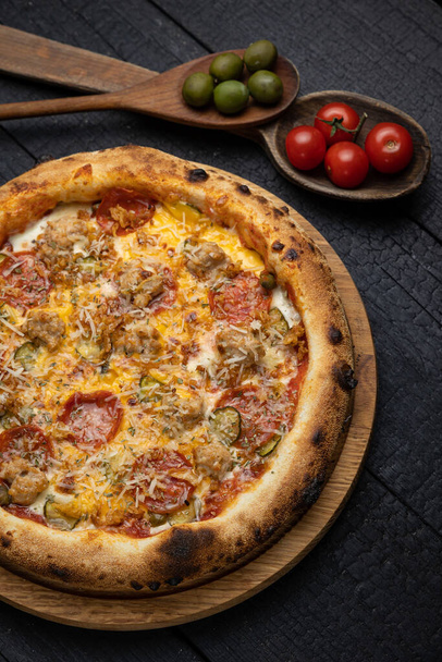tasty pizza with cheese and vegetables on a wooden dark table - Foto, Imagen