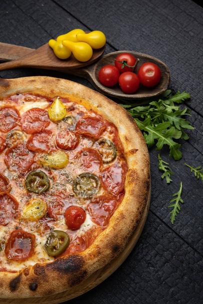 tasty pizza with cheese and vegetables on a wooden dark table - Photo, Image