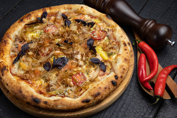 tasty pizza with cheese and vegetables on a wooden dark table - Foto, afbeelding