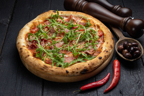 tasty pizza with cheese and vegetables on a wooden dark table - Fotografie, Obrázek