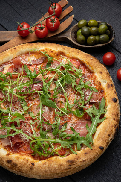 smaczna pizza z serem i warzywami na drewnianym ciemnym stole - Zdjęcie, obraz