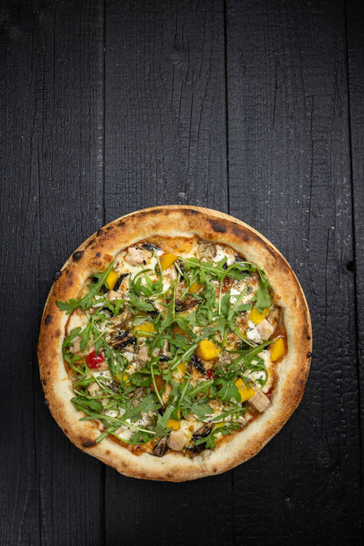 tasty pizza with cheese and vegetables on a wooden dark table - Foto, Imagen