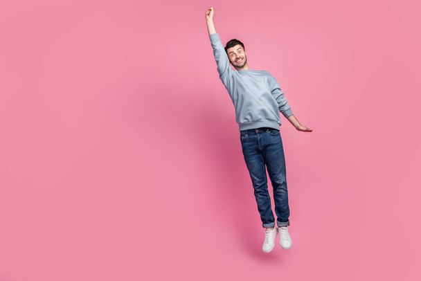 Full size photo of young handsome attractive funny man student fly up travel trip superhero hurry fast isolated on pastel pink color background. - Fotó, kép