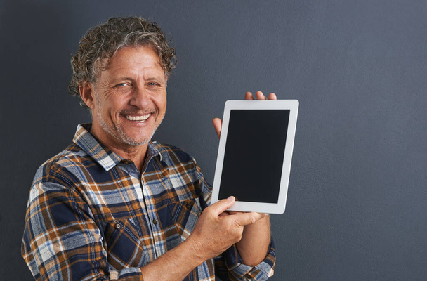 Now I can browse your website anywhere. A portrait of a happy mature man showing a tablet with a blank screen - Фото, зображення