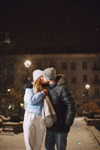 Koncepce zimních prázdnin. Venkovní noční portrét mladého páru. Posing in street of European city. - Fotografie, Obrázek