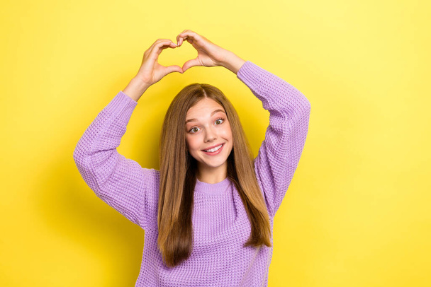 Photo of cheerful lady wear stylish violet sweater raise arm above head show heart figure empty space isolated on yellow color background. - Photo, image