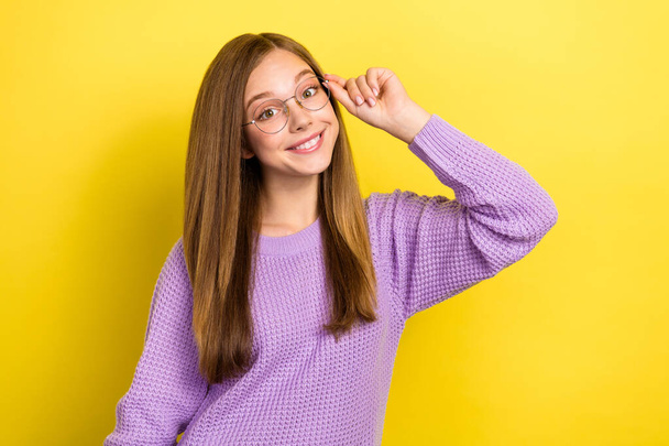 Portrait photo of young cheerful cute schoolkid girl wear knitted sweater touch eyeglasses smiling showing spectacles isolated on yellow color background. - Fotó, kép