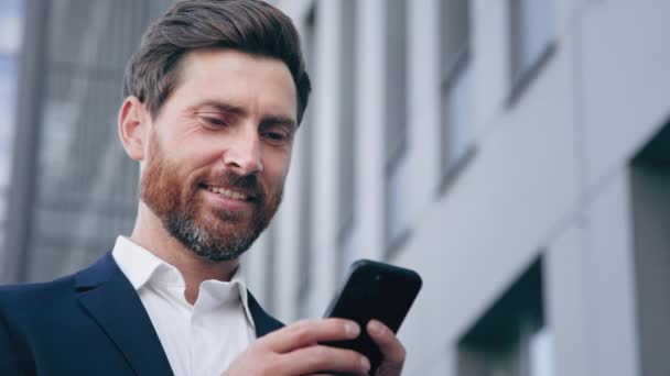 Close-up elegáns jóképű szakállas férfi gazdaság telefon küld e-mailt kommunikál az interneten sikeres üzletember tervezés szervezi menetrend segítségével mobil app okostelefon chat üzleti partnerrel - Felvétel, videó