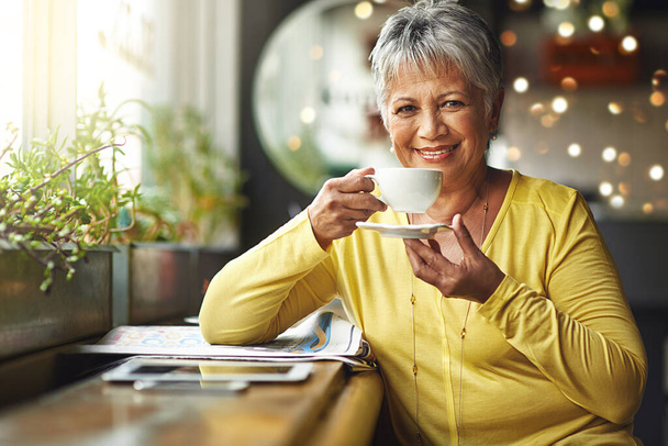 Todays mood is sponsored by coffee. Portrait of a mature woman enjoying a warm beverage at a coffee shop - Zdjęcie, obraz