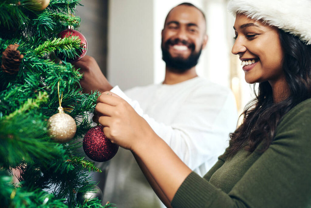 Christmas, love and couple decorating Christmas tree together for holiday, festival celebration and vacation. Bonding, marriage and happy man and woman decorate tree for festive tradition at home. - Fotoğraf, Görsel