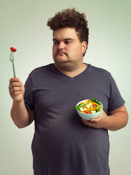 This is just not going to happen. Studio shot of an overweight man holding a bowl of salad - 写真・画像
