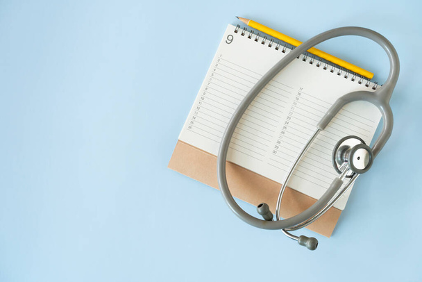 Top view of stethoscope, pencil and calendar on the blue background, schedule to check up healthy concept - Fotografie, Obrázek