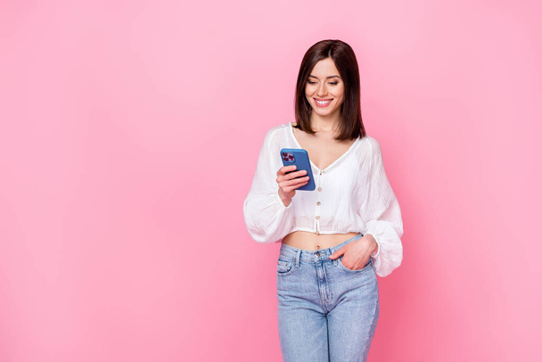 Photo of cheerful lady stylish outfit use telephone chatting texting friends read good news empty space isolated on pink color background. - 写真・画像