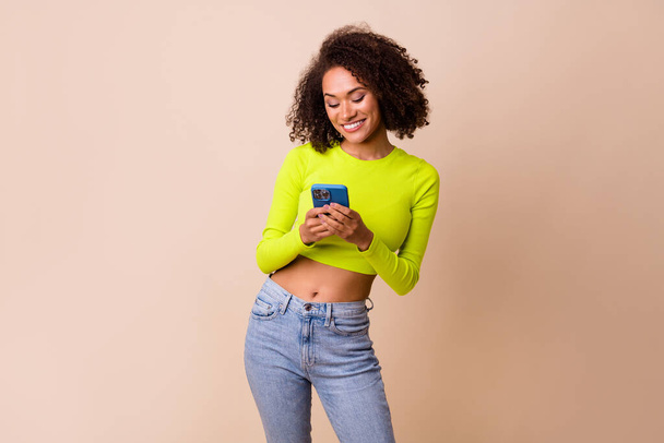 Portrait of young pretty woman smiling hold phone browsing youtube search isolated on beige color background. - Фото, зображення