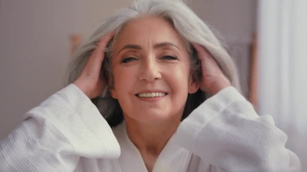 Női portré közelkép fejlövés 60-as évekbeli középkorú érett idősebb idősebb kaukázusi nő nagymama idősebb 50-es évekbeli hölgy modell hosszú fényes sima szürke haj mosolygós nézi kamera szél hajápolás - Felvétel, videó