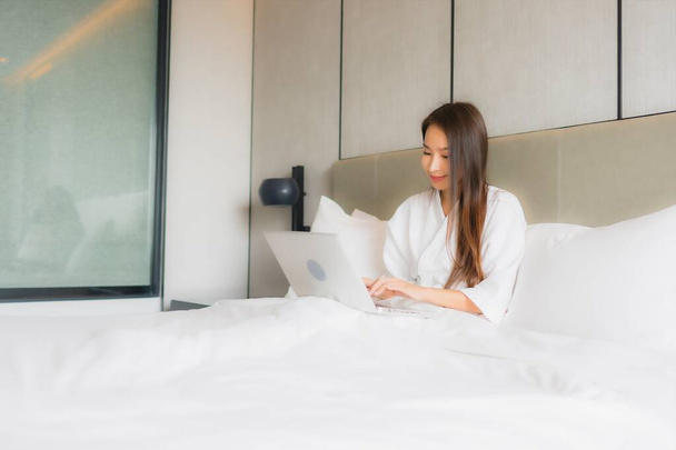 Portret piękna młoda azjatycka kobieta używać laptopa lub komputera w sypialni wnętrza - Zdjęcie, obraz