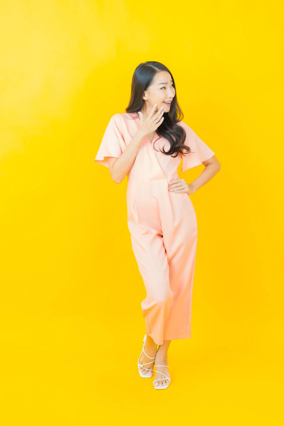 Muotokuva kaunis nuori aasialainen nainen hymyillä toiminta värillinen tausta - Valokuva, kuva