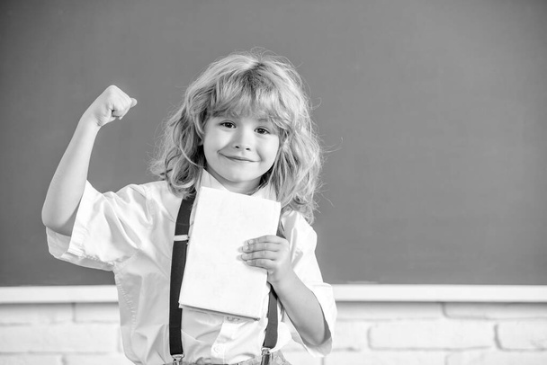 cheerful successful kid boy in bow tie in school classrrom with book, copy space, education. - Zdjęcie, obraz