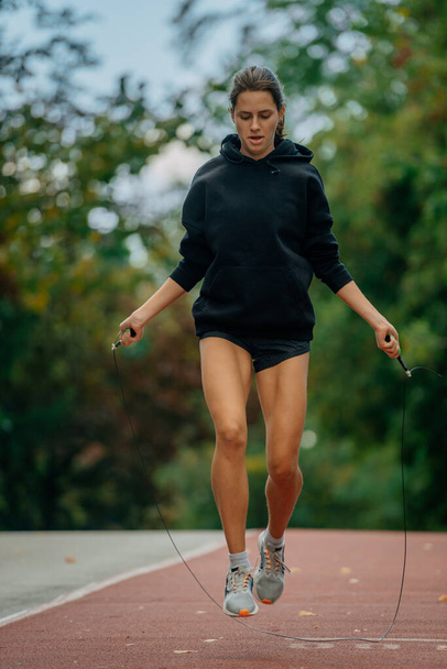 Pretty girl carefully jumping rope. She is looking at her legs while exercising - Foto, Bild