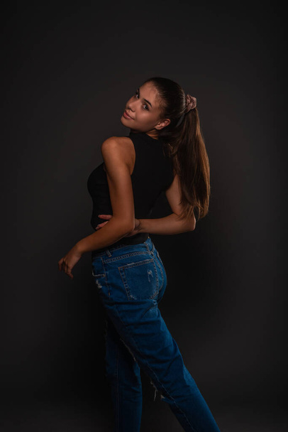 Young and attractive girl is posing from the back in studio with her hands crossed - Photo, Image