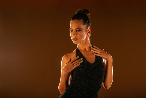 Trendy γυναικείο μοντέλο κάνει μια συνεδρία μόδας στο στούντιο. Ποζάρει με τα χέρια στο στήθος. Κοιτάζοντας στην άκρη - Φωτογραφία, εικόνα