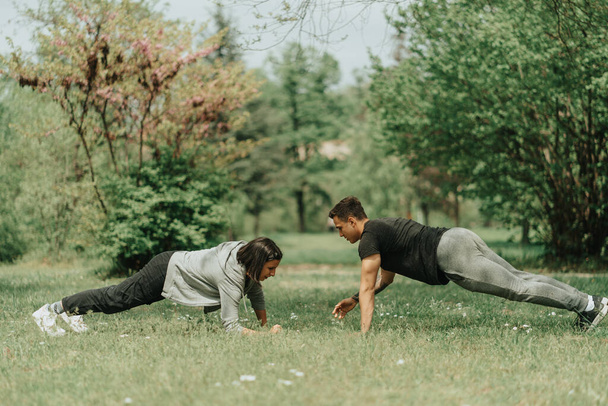 Beautiful couple having abdominal work out in the park - Photo, Image