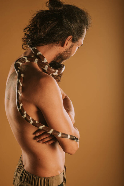 Bell'uomo con il suo serpente re californiano sulla schiena distogliendo lo sguardo - Foto, immagini
