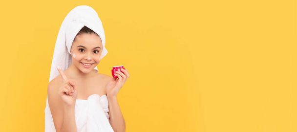 happy teen girl in shower towel applying facial cream. copy space. Cosmetics and skin care for teenager child, poster design. Beauty kid girl banner with copy space - Photo, Image