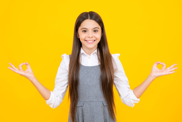 Portrait d'adolescent mignon enfant fille montrant la main montrant des annonces avec espace de copie sur fond jaune - Photo, image