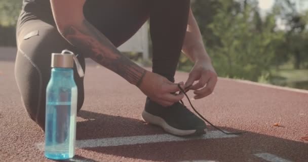 Mies sitominen lenkkarit nauhoja ennen juoksua, matala kulma, auringonlasku syksyn kohtaus - Materiaali, video