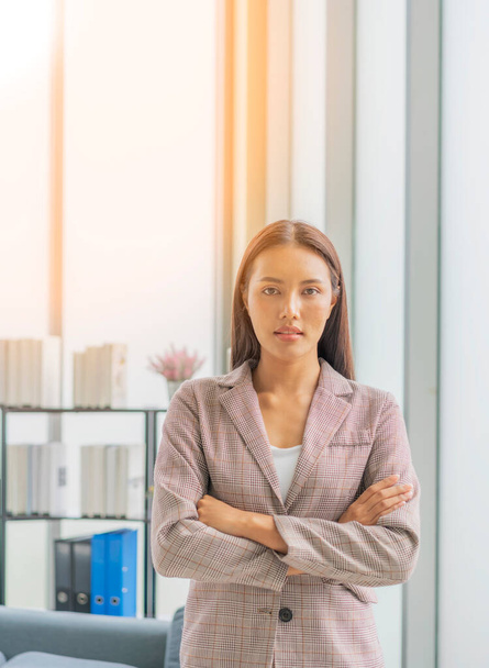 Portrait of attractive businesswoman headshot lifestyle indoors, standing in front of windows in office with sunlight flare. - Foto, Bild
