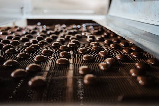 Huge factory line for sweet food and cookies production. Close up shots of industrial chocolate glazing process. - 写真・画像