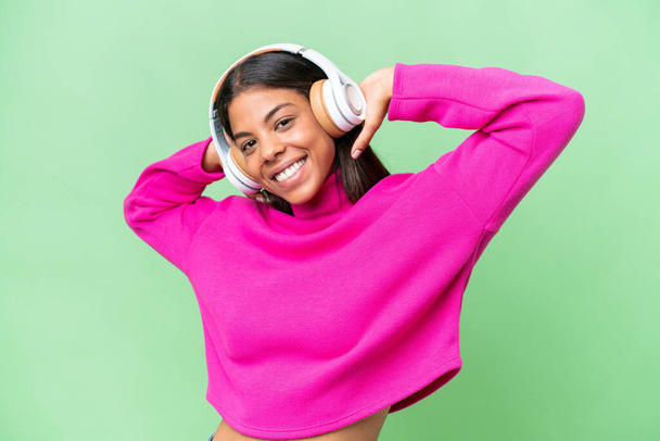 Молодая афроамериканка с изолированным фоном слушает музыку - Фото, изображение