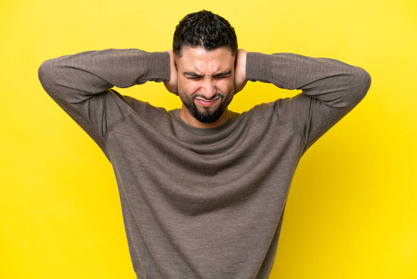 Young Arab handsome man isolated on yellow background frustrated and covering ears - Фото, изображение