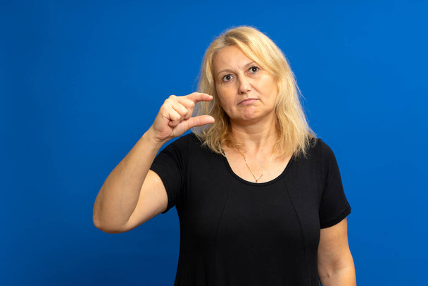 It needs a little more. Portrait of displeased skeptical woman gesturing, undersized, dissatisfied with low rating. Indoor studio shot isolated on blue color background - Photo, Image