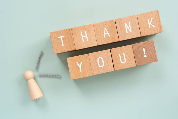 Thank you; Wooden blocks with "THANK YOU!" text of concept and a human toy. - Foto, afbeelding