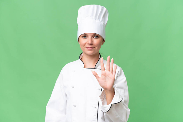 молодая женщина шеф-повар на изолированном зеленом фоне  - Фото, изображение