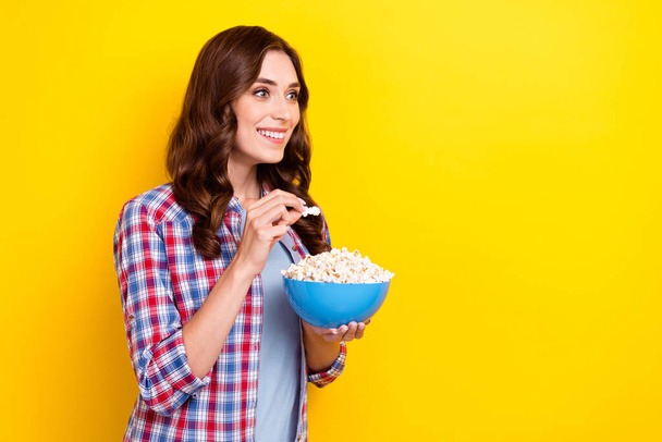 Photo of young funky girl wear checkered shirt unexpected moment movie interested look mockup eat popcorn isolated on yellow color background. - Photo, Image