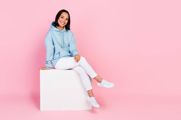 Photo of cheerful pretty glad lady dressed comfort blue clothes sitting white cube relax rest empty space isolated on pink color background. - Fotografie, Obrázek