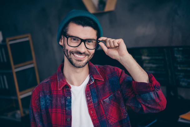 Photo of smiling cheerful coder dressed hat glasses creating good software indoors workplace workstation loft. - Фото, изображение