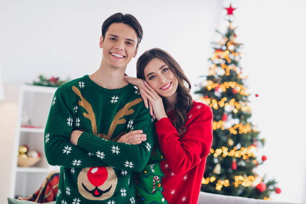 Photo portrait of young smiling confident lovely couple wear warmth sweaters idyllic spend together wintertime near xmas tree adornment indoors. - Foto, immagini