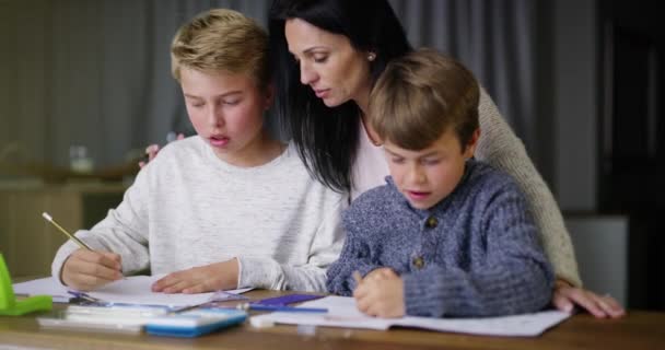 Mother help boys, with homework and for learning to assist with studying or education. Mama, sons and homeschool for teaching, child development or students writing in books, talking or reading notes. - Footage, Video