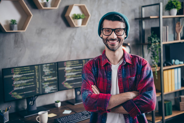 Photo of confident happy freelancer wear hat glasses arms folded smiling indoors workplace workstation loft. - Foto, imagen