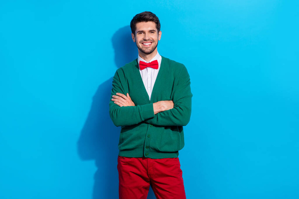 Photo of positive funky man wear x-mas green cardigan smiling arms crossed isolated blue color background. - 写真・画像