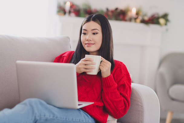 Photo of beautiful sweet girl wear xmas red pullover enjoying mulled wine watching film modern device indoors home room. - Zdjęcie, obraz