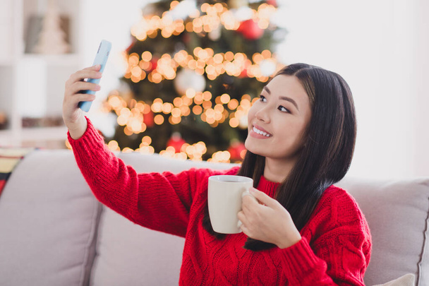 Portrait of beautiful nice positive charming woman with straight hairdo wear red knit pullover hold cup making selfie in house indoors. - Zdjęcie, obraz