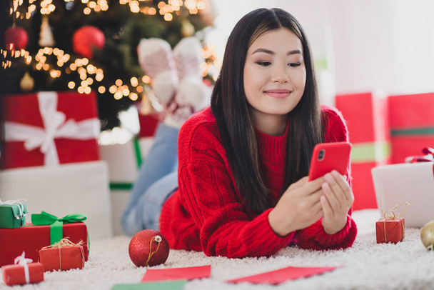 Photo of dreamy beautiful girl wear xmas red pullover typing greetings modern gadget indoors home room. - Foto, imagen