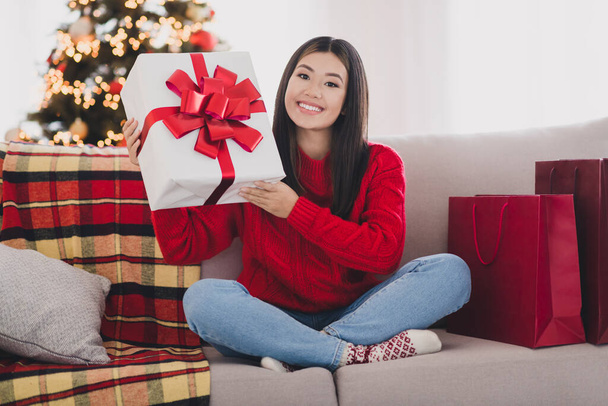 Fotografie sladké hezká dívka nosit vánoční červený svetr příprava Noel dárek sedací pohovka vnitřní domácí pokoj. - Fotografie, Obrázek