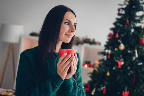 Photo of cute charming girl wear xmas green pullover enjoying coffee aroma indoors home room. - Foto, afbeelding